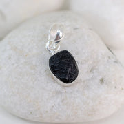 Black stone pendant on silver chain against a white stone background